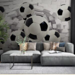 Papier peint Des ballons de football qui traversent un mur