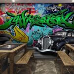 Papier peint Voiture noire avec roues devant un mur coloré